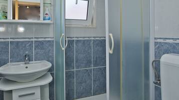 Une salle de bain moderne avec une douche à parois de verre, un lavabo avec un miroir et des toilettes.