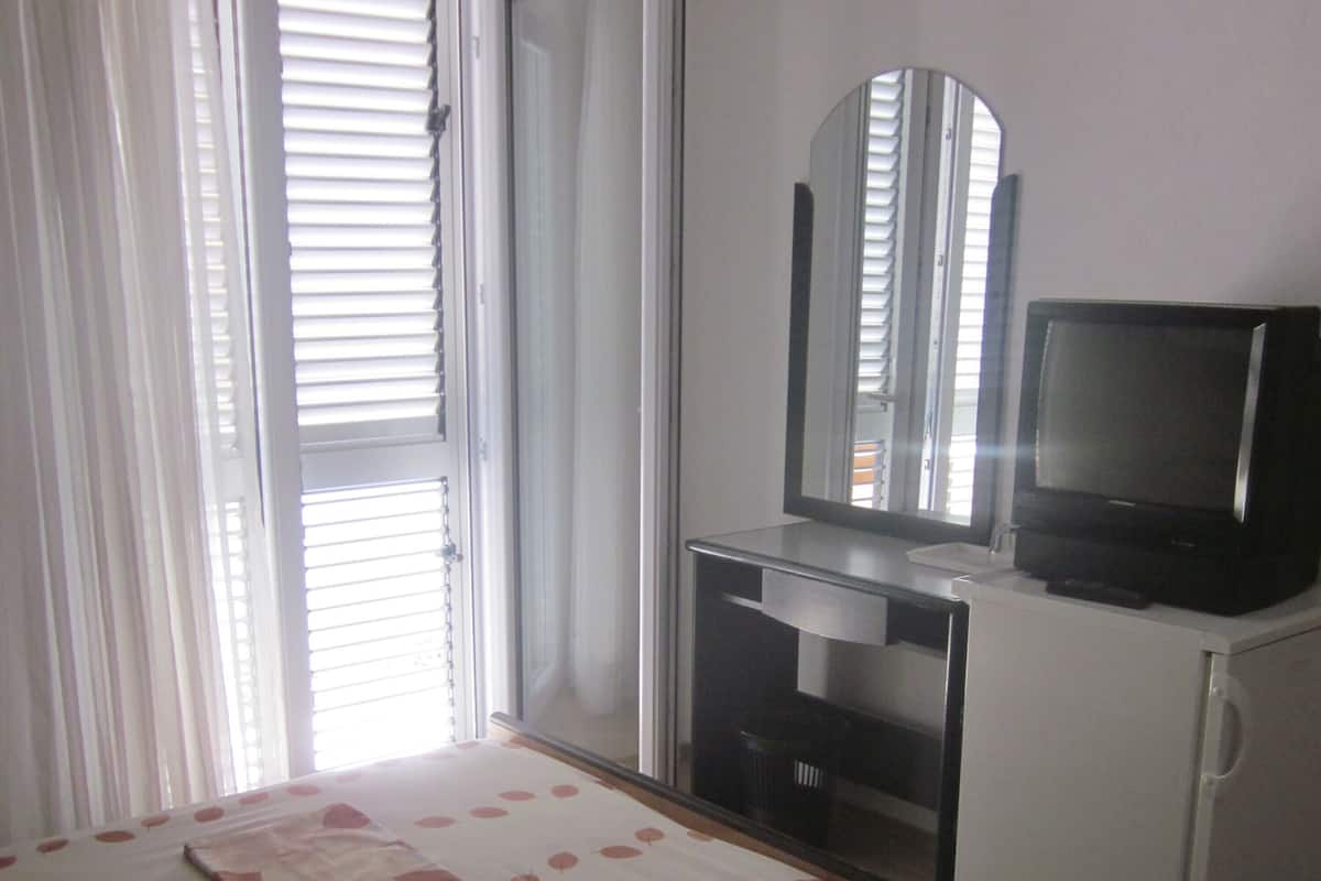Un dormitorio con cama, televisor, espejo y puerta corredera.