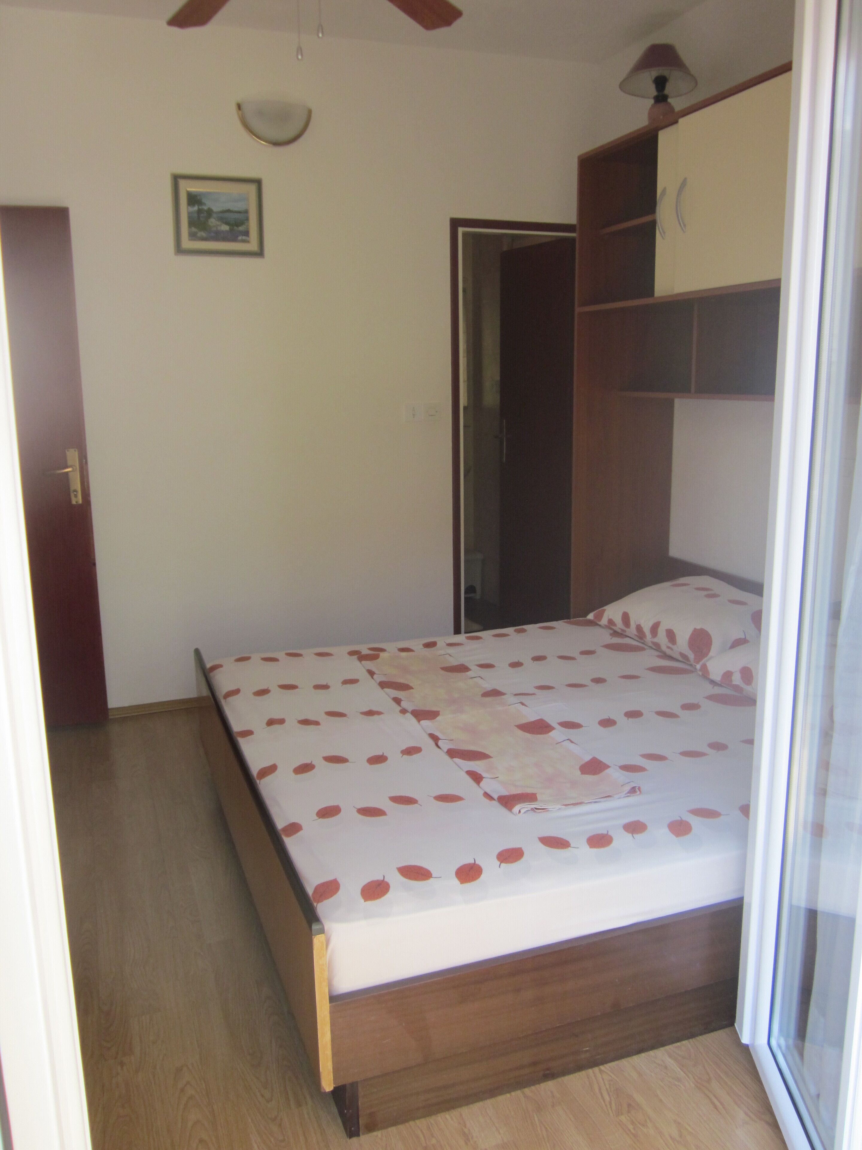 Un dormitorio con cama, armario de madera y una puerta.