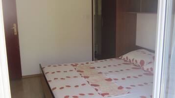 Un dormitorio con cama, armario de madera y una puerta.