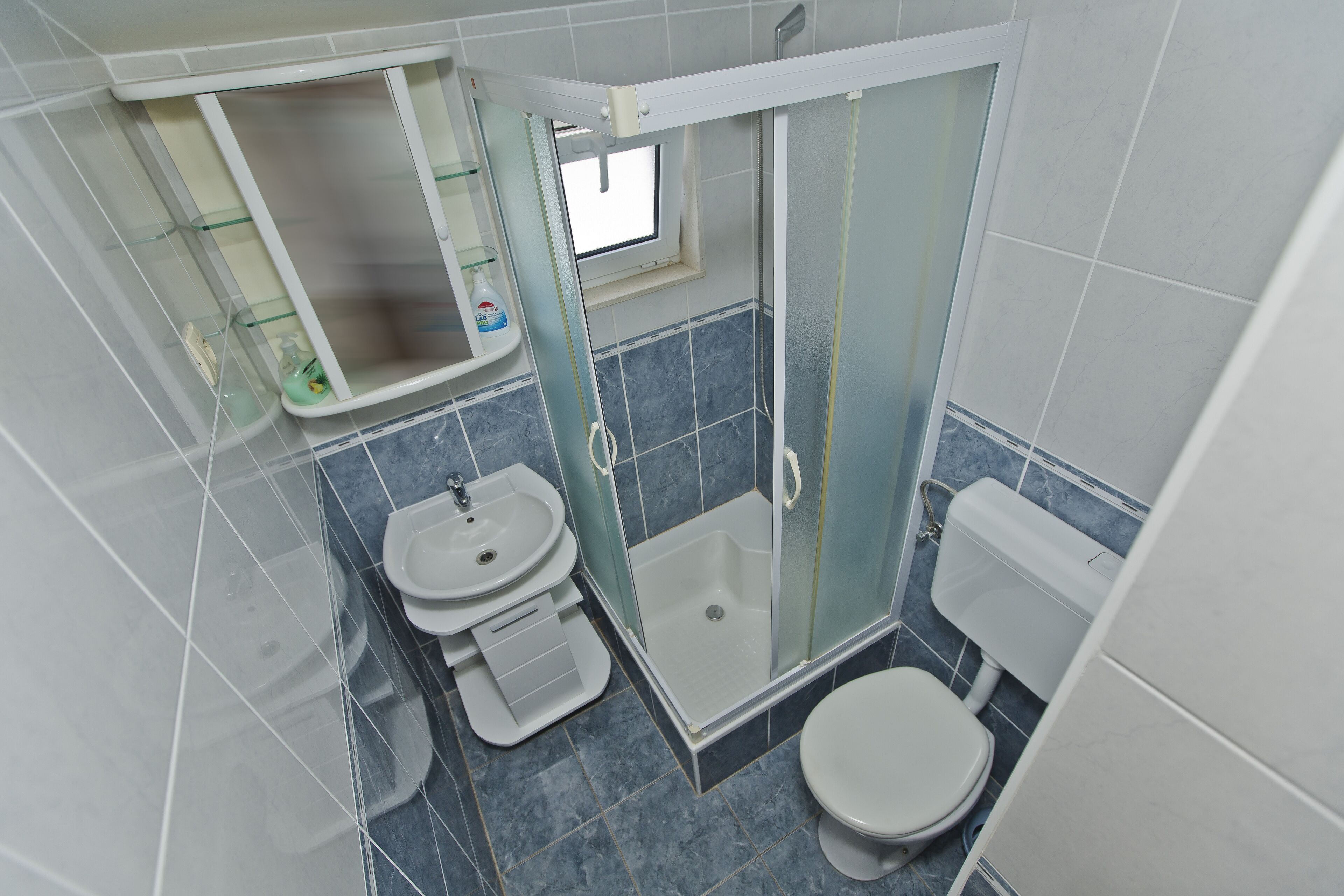 A bathroom with a glass-enclosed shower, a sink, and a toilet.