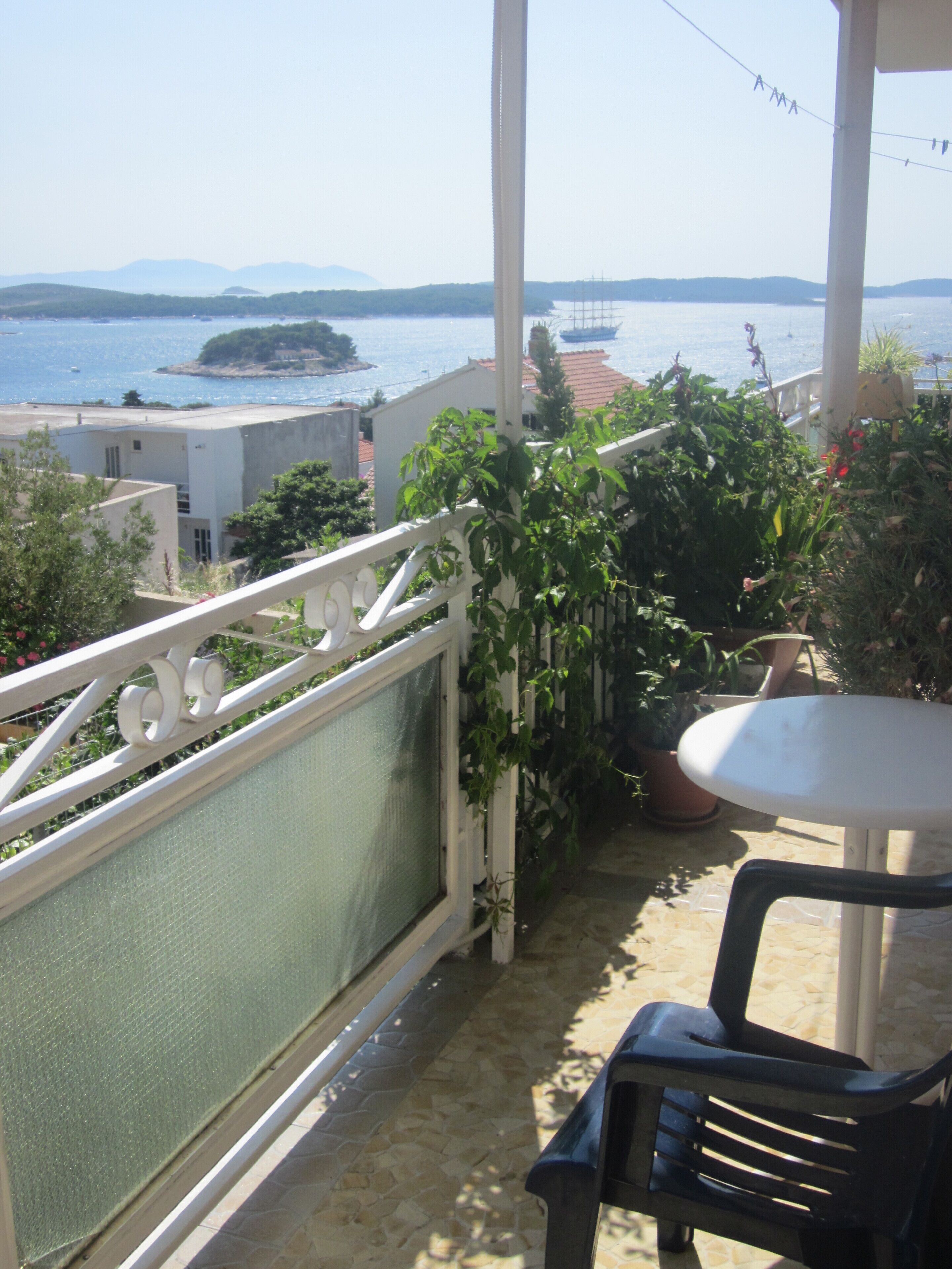 Un balcon avec vue sur la mer, une table et des plantes en pot.
