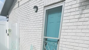 A white brick building with a teal door, a small porch with two green metal chairs, and a black doormat. - Cozy and Modern apartment (Seffner)