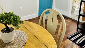 A dining area with a wooden table, chairs, a blue door, and wall-mounted decor. - Cozy and Modern apartment (Seffner)