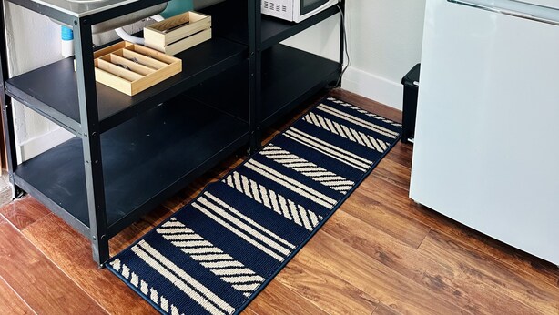 A compact kitchen with a built-in microwave, a coffee maker, and a sink. There is a black metal shelf above the counter holding dishes and a small plant. - Cozy and Modern apartment (Seffner)