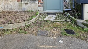 Un edificio con facciata in mattoni, una porta verde e una piccola finestra.