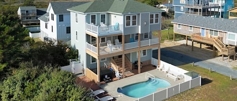 A multi-story residential building with a pool, outdoor seating, and a view of the ocean.