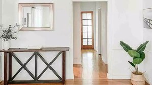 A spacious room with hardwood flooring, a ceiling fan, a wooden console table, and a potted plant. - Cozy Home in a Quiet Neighborhood

 (Vallejo)