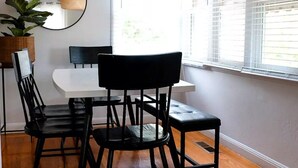 A dining area with a white table, black chairs, and a woven pendant light. - Cozy Home in a Quiet Neighborhood

 (Vallejo)