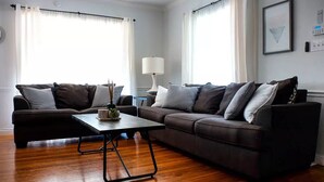 A living room with two sofas, a coffee table, and a lamp. - Cozy Home in a Quiet Neighborhood

 (Vallejo)