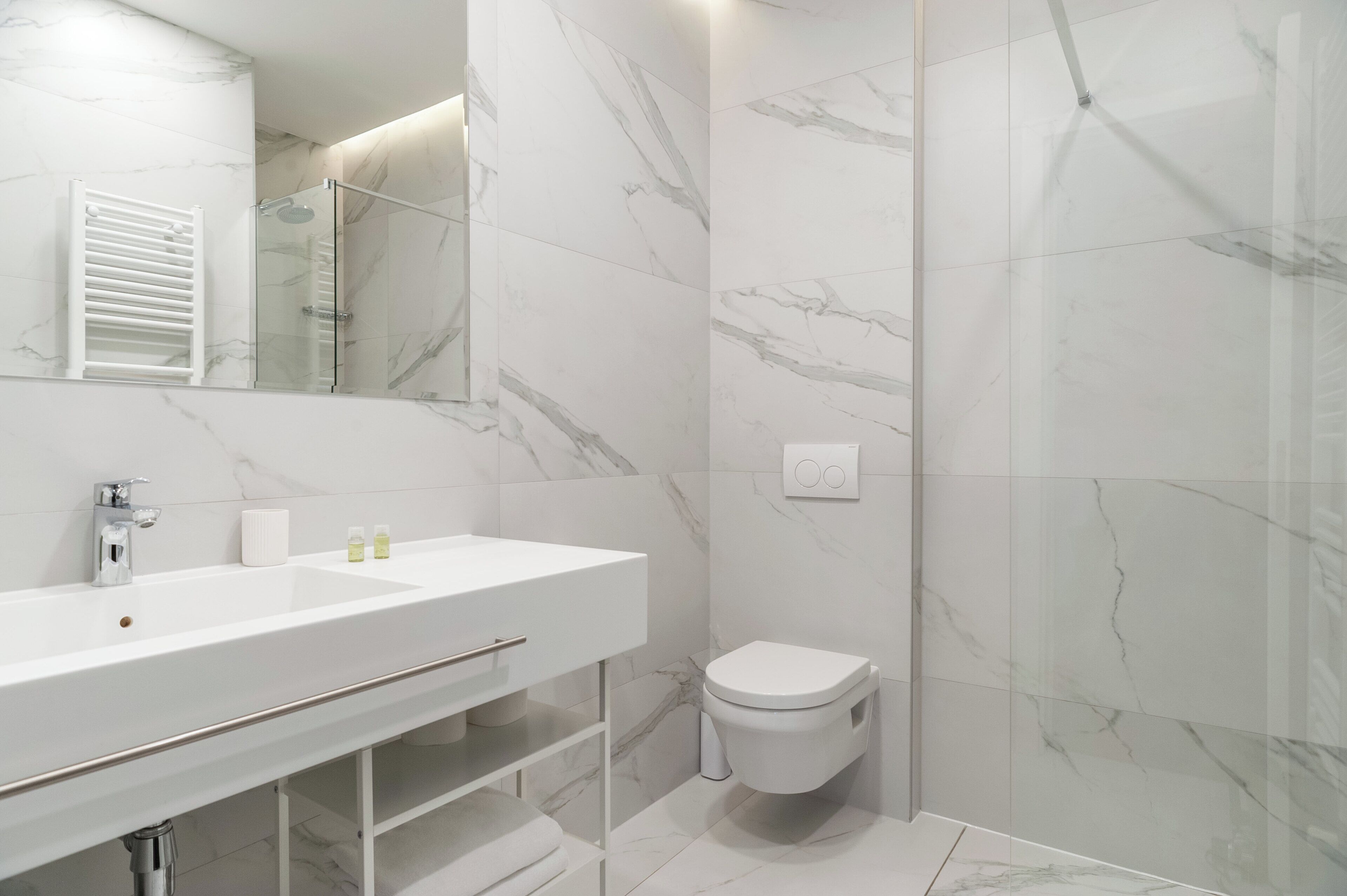Une salle de bain moderne avec un lavabo blanc, un miroir et des toilettes.
