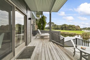 A wooden deck with a table and chairs, overlooking a body of water and a golf course. - Great Location, popular East Beach neighborhood (Kiawah Island)