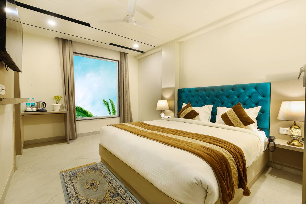 A hotel room with a large bed, a window with curtains, a bedside table with a lamp, and a ceiling fan.