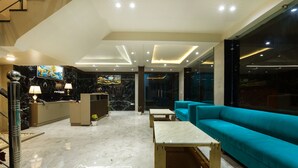 Een moderne lobby met een receptiebalie, een zithoek en een groot raam.