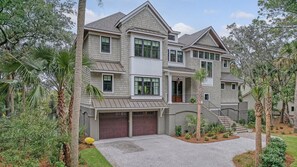 A two-story house with a covered garage, a balcony, and a landscaped driveway. - New Build, pool, marsh views (Kiawah Island)