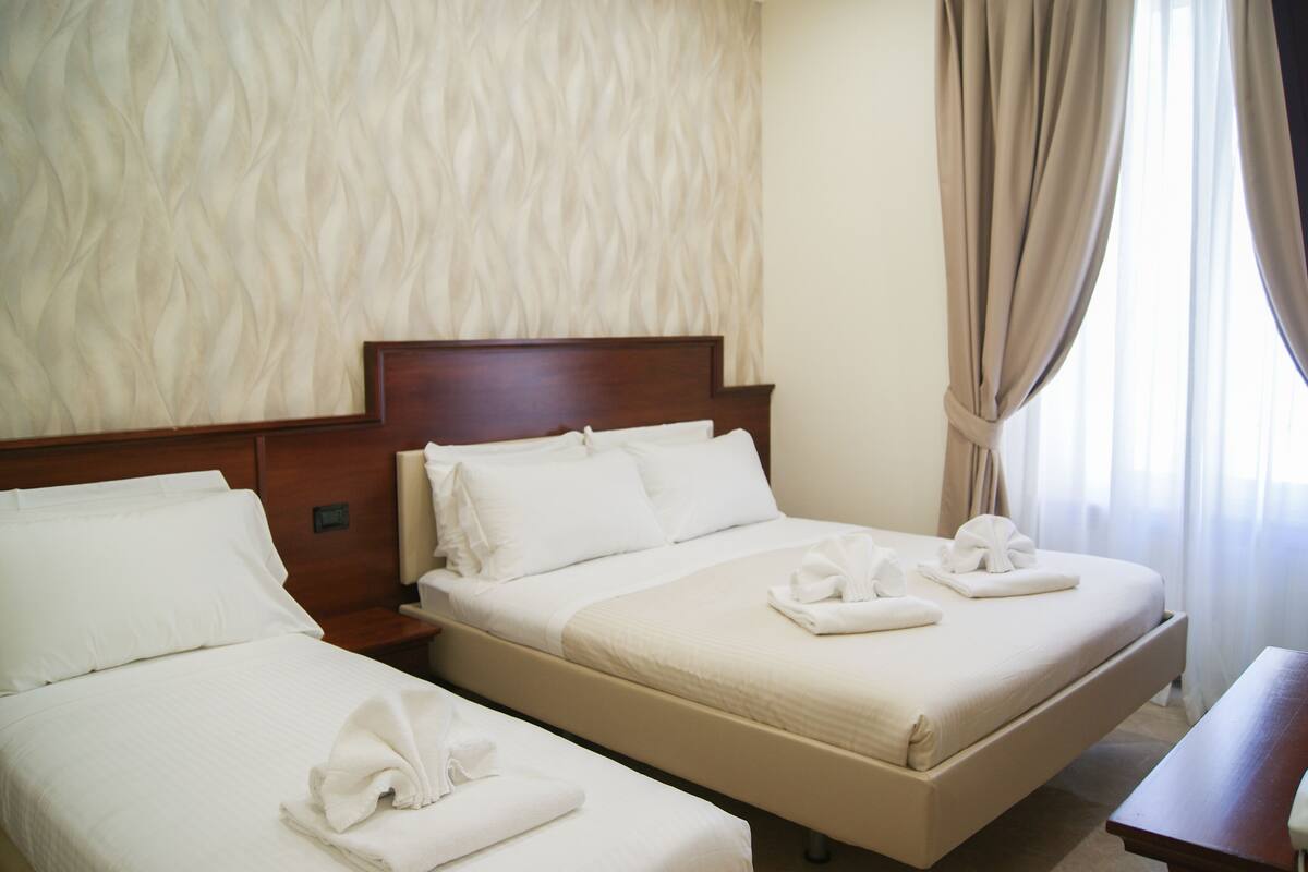 A hotel room with two beds, a wooden headboard, and a bedside table.