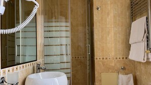 Une salle de bain avec un grand lavabo blanc, une douche en verre et un porte-serviettes.