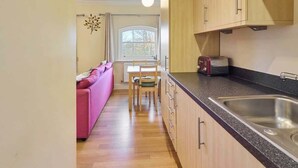 A compact kitchen with wooden cabinets and a stainless steel sink.
