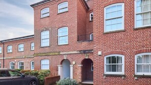 A red brick building with multiple windows and a car parked in front.