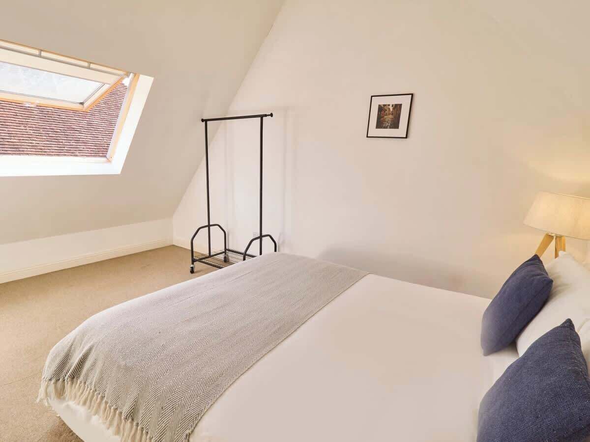 Une chambre à coucher avec un lit, une fenêtre, un tableau au mur et une lampe.