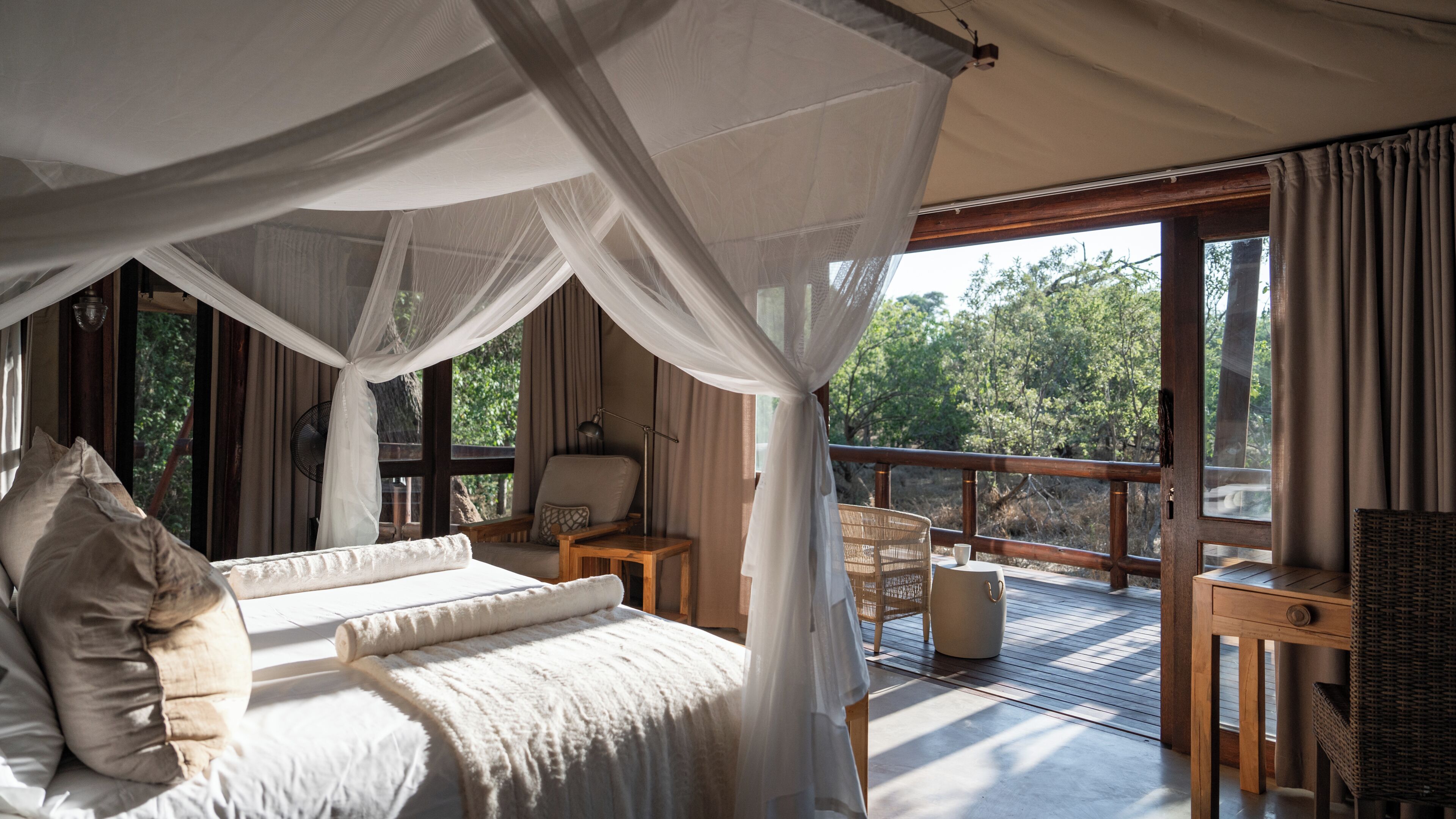 Un dormitorio con cama a dosel, una mesa de madera, una silla y vistas al exterior.