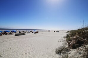 A sandy beach with blue umbrellas and beach chairs. - Sunset Rentals | Shipmaster 1703 | Dog Friendly (Hilton Head Island)