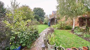 Ein Garten mit einem Ziegelweg, der zu einem rustikalen Gebäude führt.