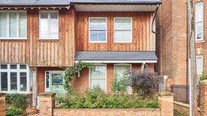 Ein zweistöckiges Holzhaus mit Backsteinfassade, einem Vorgarten und einer sichtbaren Haustür.