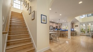 A spacious kitchen with wooden flooring, a dining area, and a staircase with framed pictures.