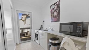 Une cuisine compacte équipée d’un lave-linge, d’un four à micro-ondes et d’une poubelle.