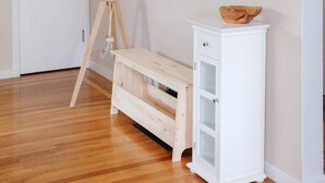 Ein Flur mit einer hölzernen Bank, einem weißen Schrank und einer Stehlampe.