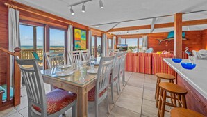 Un espace repas avec vue sur la plage, des murs en bois et un grand tableau.