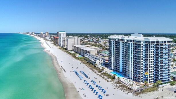 A coastal hotel with multiple floors, a beach with umbrellas, and a clear view of the ocean. - Watercrest 302 Amazing VIEW, Pool, Hot Tub, Tennis, Gym, FREE Golf & Perks! (Panama City Beach)