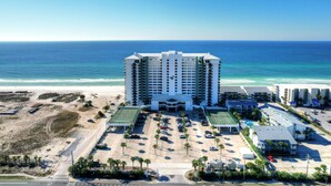 A high-rise hotel with a central entrance, a parking lot, and a beach view. - Watercrest 302 Amazing VIEW, Pool, Hot Tub, Tennis, Gym, FREE Golf & Perks! (Panama City Beach)