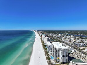 A coastal cityscape with a long sandy beach, high-rise buildings, and a clear blue sky.