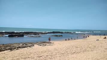 Na praia, areia branca, guarda-sóis, toalhas de praia
