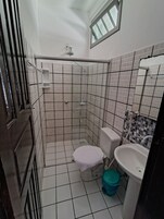 Un baño pequeño con ducha, inodoro y lavabo.