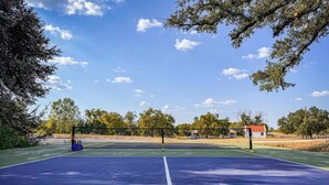 A tennis court with a net, surrounded by trees and a clear sky. - Little Dutch Cabin 101-12 Min to Magnolia-baylor (Waco)