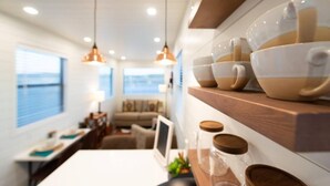 Une cuisine moderne avec des étagères en bois, des luminaires suspendus et un coin repas comprenant une table et des chaises.