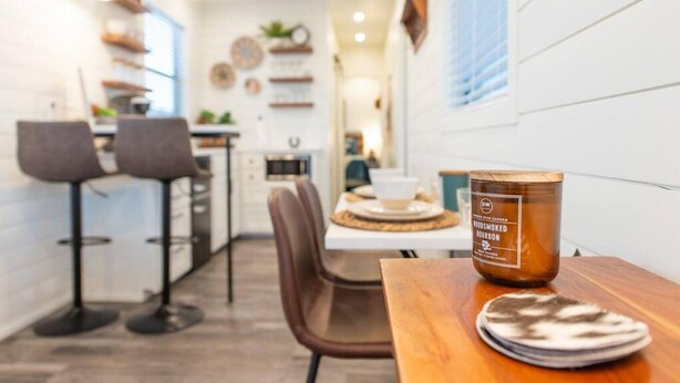 Une cuisine moderne avec des tabourets de bar, une table en bois avec une bougie et une vue sur la salle à manger.