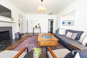 A modern living room with a fireplace, a sofa, a coffee table, and a television.