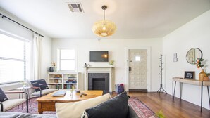 A modern living room with a fireplace, a television mounted above it, a coffee table, and a sofa.