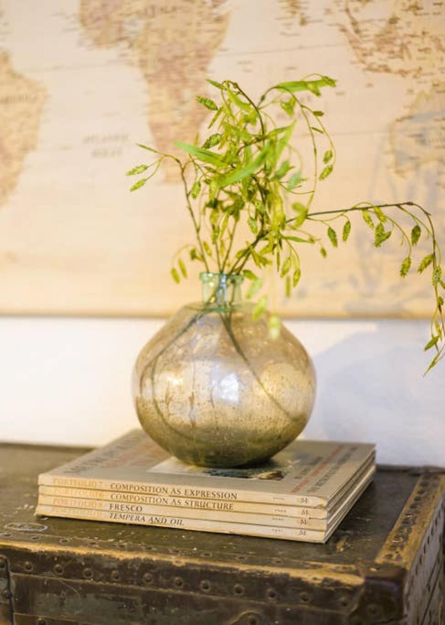 Un vase avec une plante, posé sur une pile de livres.