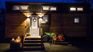 A wooden cabin with a front porch, steps, and a wreath above the door. - Montana Escape Tiny House in Waco 12 min to Magnolia and Baylor (Waco)