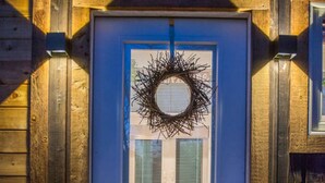 A wooden exterior with a blue door, a wreath, and a potted plant. - Montana Escape Tiny House in Waco 12 min to Magnolia and Baylor (Waco)