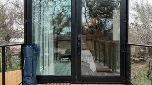 Um deck de madeira com porta de vidro que dá para uma área externa coberta.