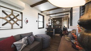 Un salon chaleureux avec un canapé, une table basse et un coin cuisine à l’arrière-plan.