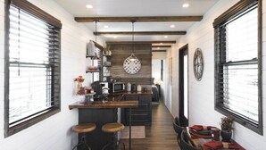 Une cuisine étroite avec un îlot central, des poutres en bois au plafond et une horloge au mur.