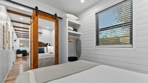 A bedroom with a large bed, a wooden door, a closet, and a window with blinds. - Pecan Grove Container Tiny Home Country Setting 12 min to Baylor Magnolia (Waco)
