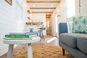Un salon chaleureux avec un canapé gris, une petite table ronde sur laquelle sont posés des livres et un tapis à motifs.